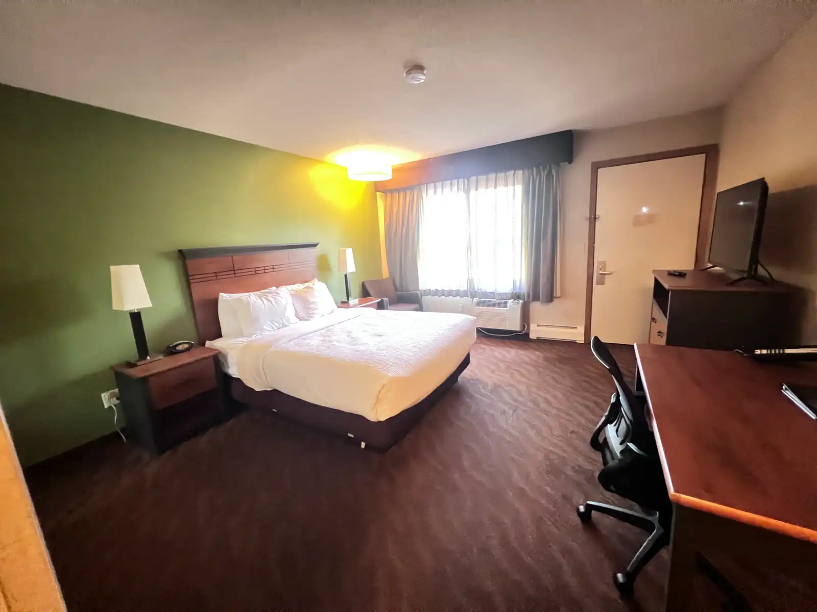 An Accessible Queen room with a wide clear floor area, a desk and an armchair by the window