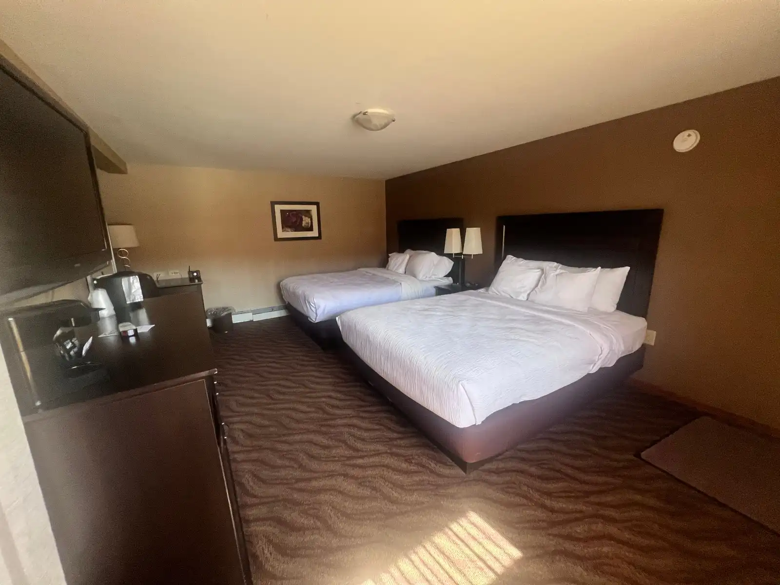 Two queen beds in a suite, with the coffee station and fridge on the wall opposite
